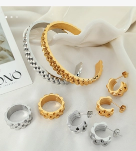 Detailed view of layered wavy gold and silver jewelry set on soft white fabric