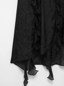 Close-up of ruffled hem and irregular pointed design on a sheer black maxi dress