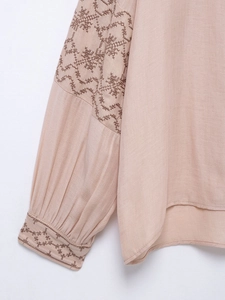 Detail of embroidered lantern sleeve on pink cotton linen blouse showing intricate patterns