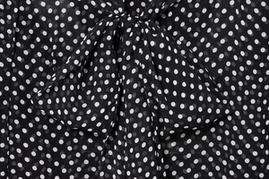 Detailed close-up of bow tie collar and white polka dot pattern on black chiffon fabric