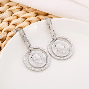 Detail of silver vintage coin earrings with chain link on white ceramic tray