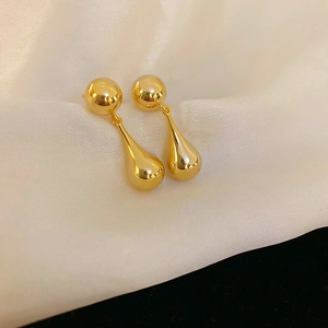 Gros plan de boucles d'oreilles goutte d'or polies sur un tissu en soie blanche