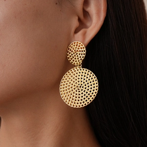 Gros plan de boucles d'oreilles dorées géométriques doubles rondes à texture tissée