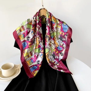 Detail of a square silk scarf with vibrant cat patterns draped over a black dress