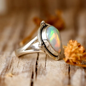 Vue macro d'une bague vintage en argent avec opale colorée sur surface en bois