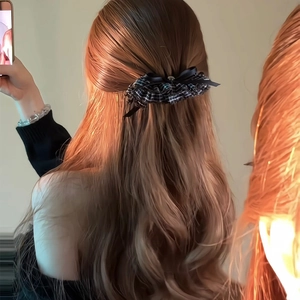 Detail of vintage black and white grid bow hair clip styled on elegant wavy hair