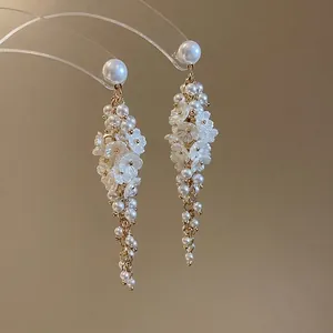 Elegant long pearl tassel earrings with white flower charms on a gold plated metal base
