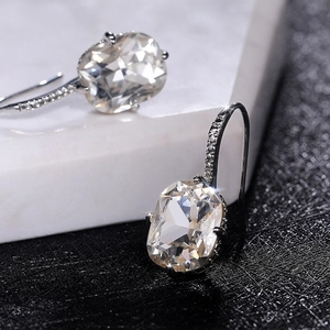 Close-up of square zircon earrings with micro-pave hooks on black and white stone base