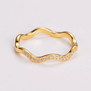 Macro shot of gold wave-shaped ring with pavé-set clear zircons on a white background