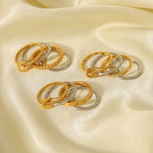 Close-up of layered titanium steel rings with rhinestones on cream silk fabric