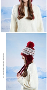 Détail d'un bonnet d'hiver rouge à motifs jacquard de flocons et grand pompon