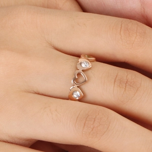 Bague ajourée cœur en or rose avec zircons blancs sur le doigt du mannequin en gros plan