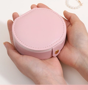 Boîte à bijoux ronde rose en cuir PU tenue en main avec fermoir doré brillant