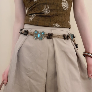 Detail of bohemian woven waist chain with metal butterfly buckle and turquoise wood beads