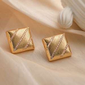 Goldene quadratische Ohrstecker mit diagonaler Textur und Zirkonia auf beiger Seide