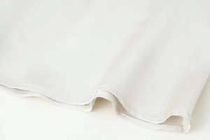 Detailed close-up of smooth white satin fabric with precise double-stitched hem finish