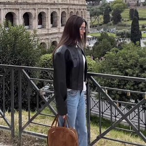 Chic black faux leather cropped jacket styled with blue jeans near the Colosseum
