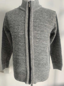 Close-up detail of grey knitted cardigan showing coarse grain texture and metal zipper