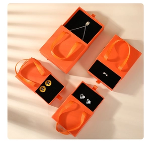 Detail of orange drawer jewelry boxes with black flocking lining and ribbon handles