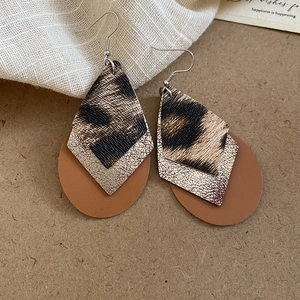 Macro detail of triple-layer teardrop earrings with leopard print and golden texture