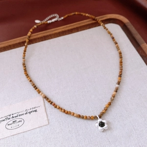 Détail d'un collier de perles avec pendentif fleur en argent sur fond en coton vintage