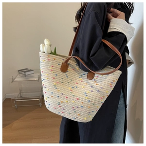 Detail of a beige woven cotton tote with colorful polka dots and leather handle