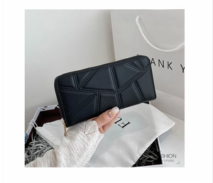 Detail of black quilted faux leather long wallet with triangle stitching and gold zipper
