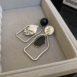 Détail de boucles d'oreilles géométriques asymétriques en argent avec accents d'émail noir