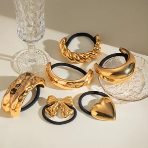 Golden metal hair ties featuring heart, bow, and twisted designs on beige background