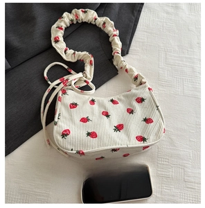 Detail of cream corduroy shoulder bag with strawberry print and ruched cloud strap