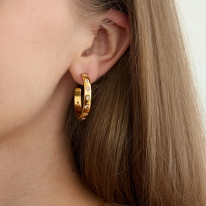 Gros plan de boucles d'oreilles créoles en acier doré 18K avec zircons sur le mannequin