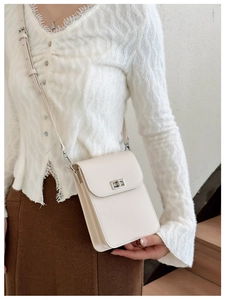 Detail shot of a minimalist cream phone bag with adjustable strap worn by a model