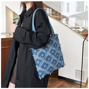 Detail of distressed denim tote bag featuring star patterns and frayed patchwork design