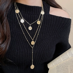 Three-layer gold coin pendant necklace styled on a black turtleneck sweater for women
