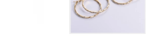 Close-up of golden wavy hoop earrings with sparkly rhinestones in detailed macro view