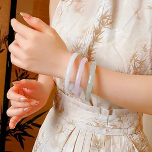 Three elegant round bangles in white, purple and grey worn with a chic qipao dress