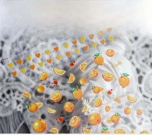 Detailed close-up of fruit nail stickers with orange slices and watercolor hearts