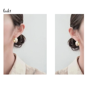 Detail shot of French-style gold and pearl white enamel hoop earrings worn by a model