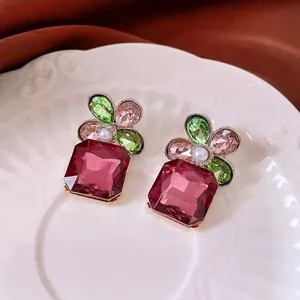 Floral stud earrings with colorful crystals and pearls displayed on white ceramic plate