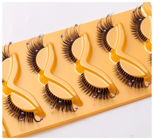 Detail of 5 pairs of cat-eye false eyelashes with colorful beads on a yellow tray