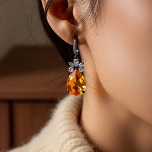 Macro shot of vintage teardrop earrings with amber zircon and dark metallic setting