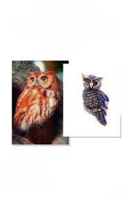 Detailed close-up of a luxury owl brooch featuring deep blue crystals and rose gold plating