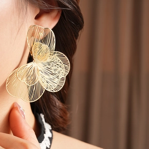 Gros plan d'un mannequin portant de grandes boucles d'oreilles fleurs ajourées dorées
