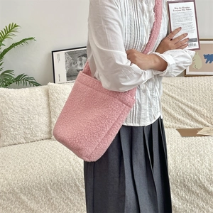 Détail du sac seau rose en peluche avec texture sherpa douce porté à l'épaule sur mannequin