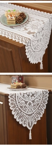 Close-up of white lace table runner with intricate hollow patterns and elegant tassels