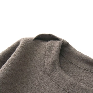Detailed close-up of high-density knit fabric and collar seam on dark taupe poncho
