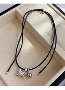 Gros plan du pendentif pégase argenté et perle grise sur un collier en cordon noir