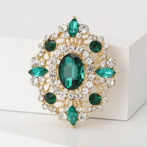 Vintage gold brooch with green oval rhinestones and crystals on white display stand