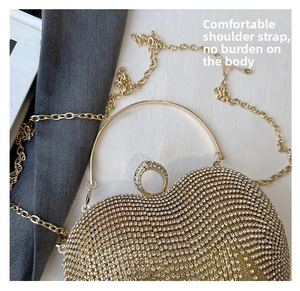 Detail of a heart-shaped evening clutch bag with gold rhinestones and chain strap