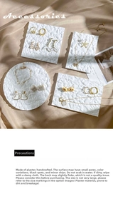 Macro view of gold earrings and pearl bracelets on a white textured display tray